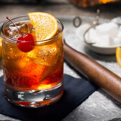 Whiskey sour cocktail with a lemon wedge and red cherry