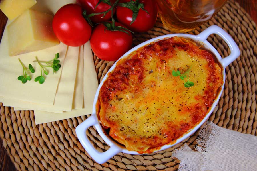 Spaghetti pie covered in sauce and cheese in a baking dish