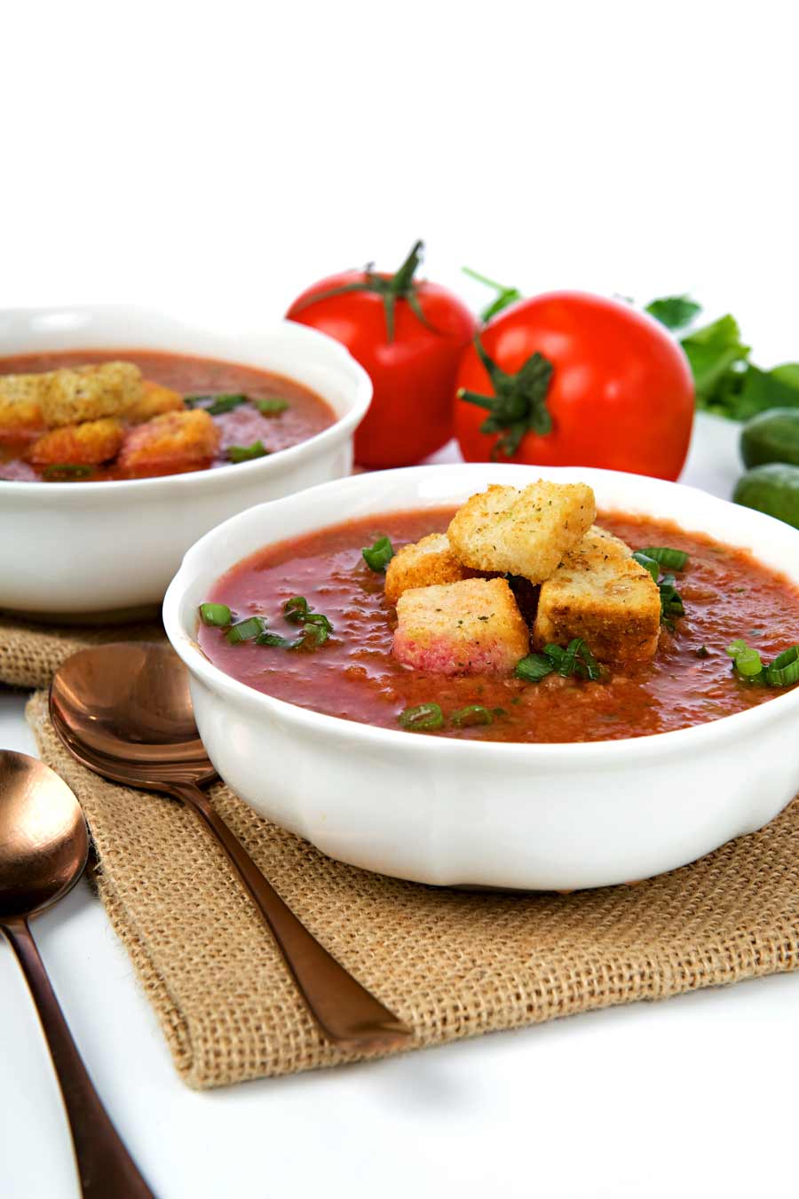 2 bowls of gazpacho with croutons on top.