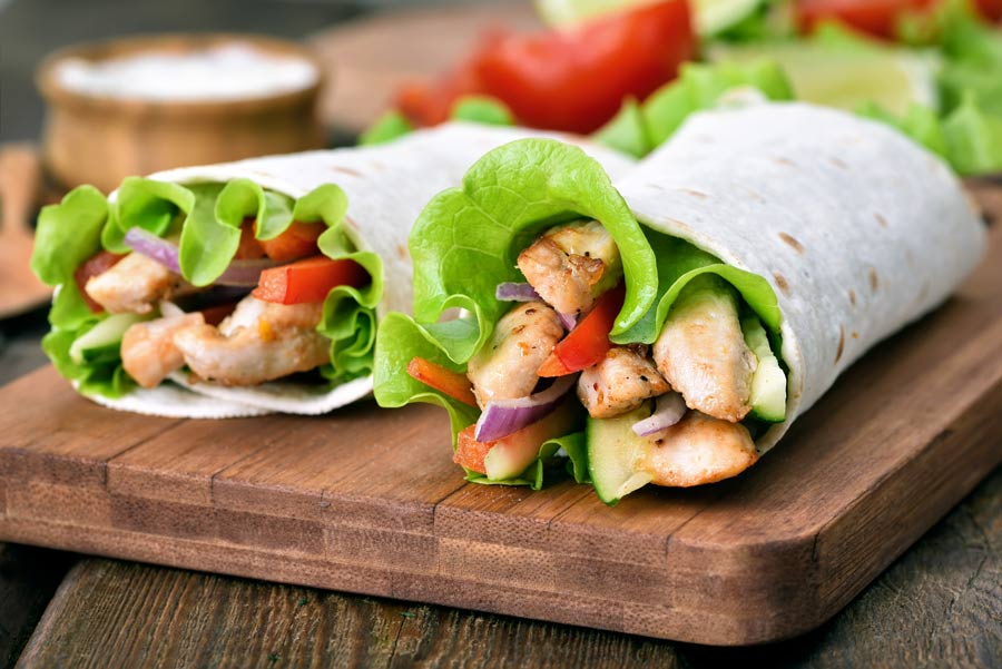 A tortilla filled with chicken fajita meat and lettuce and tomato