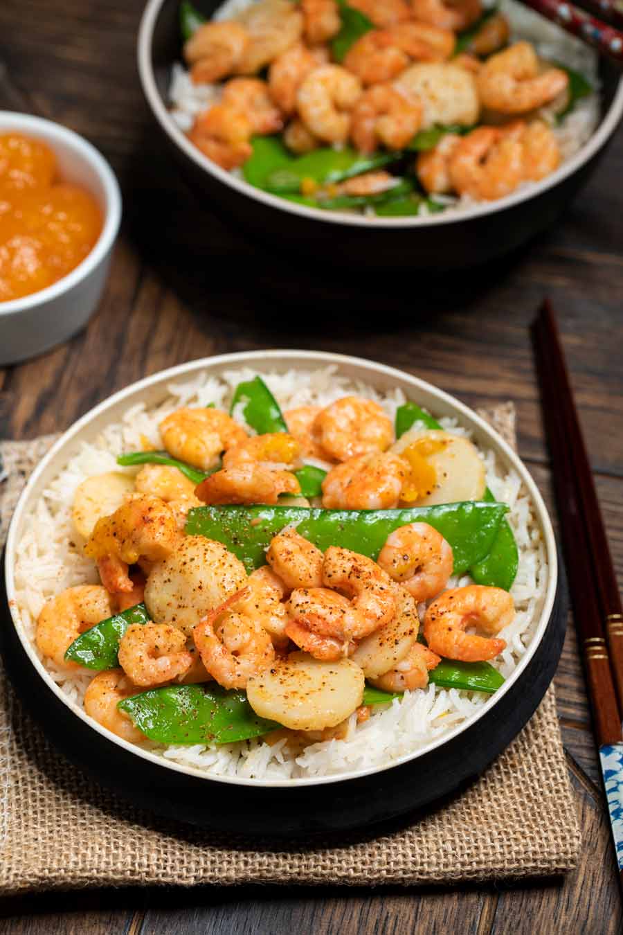 2 bowls of asian stir fry with shrimp and a side of orange marmalade.