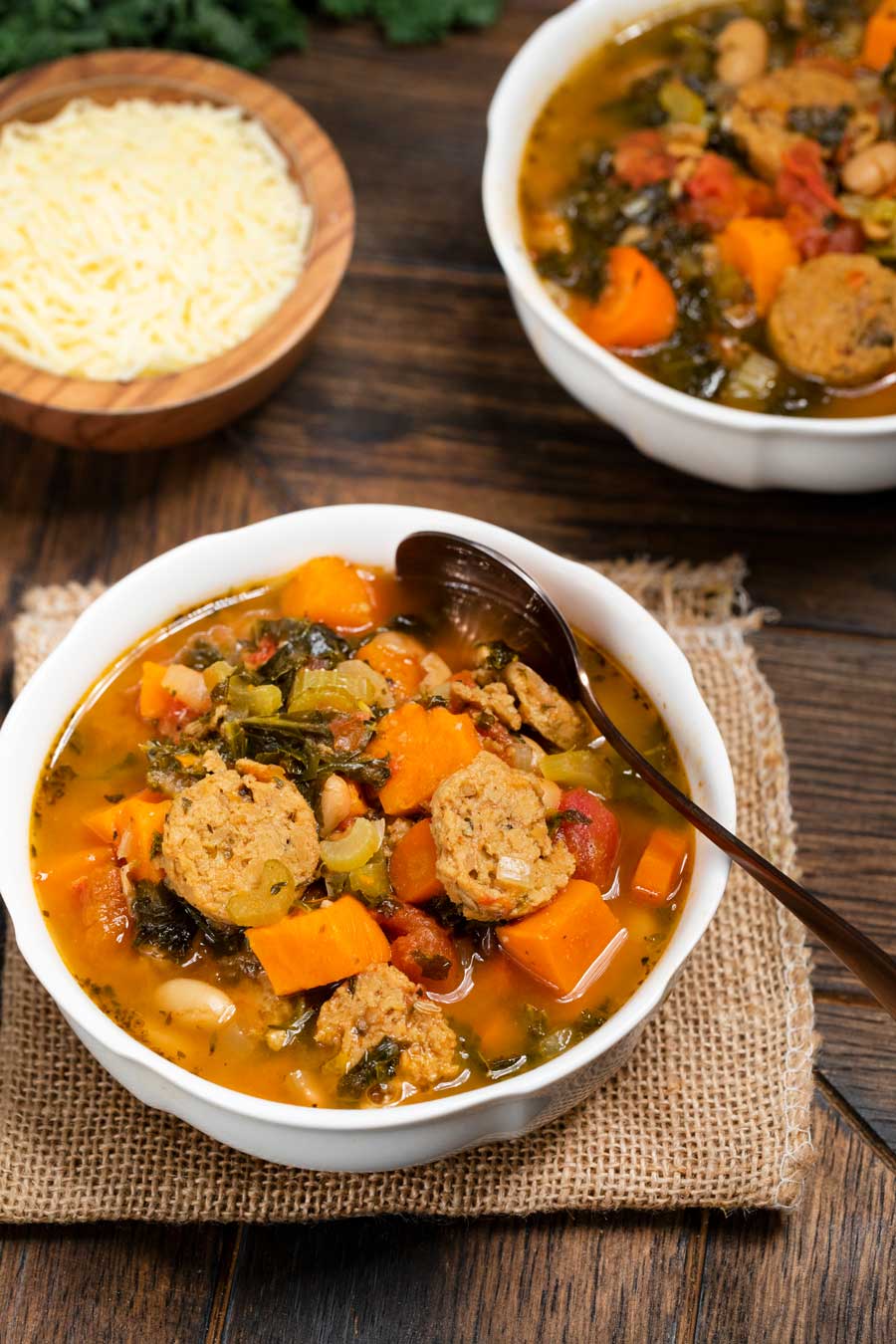 A bowl of minestrone soup with turkey sausage, carrots and sweet potatoes.