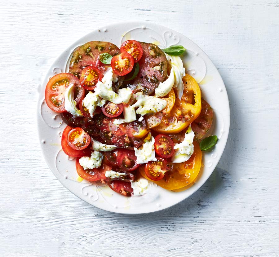 A plate of tomatoes with mozzarella cheese on top.
