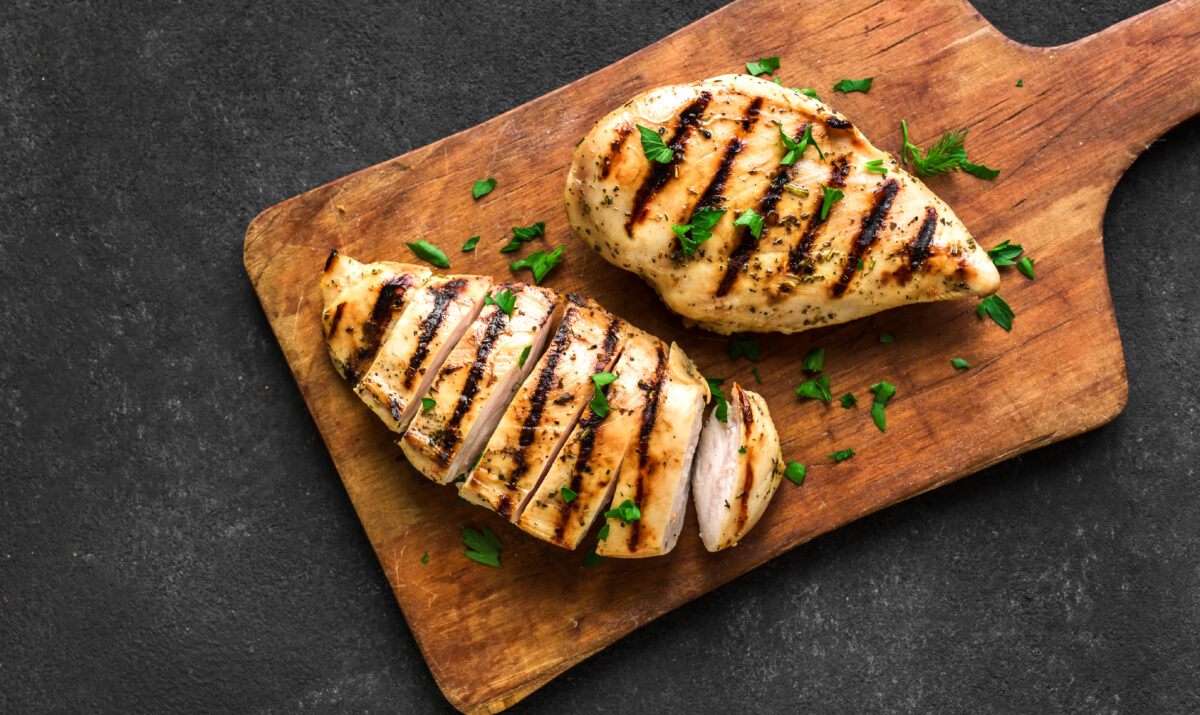Grilled chicken on a cutting board, topped with parsley