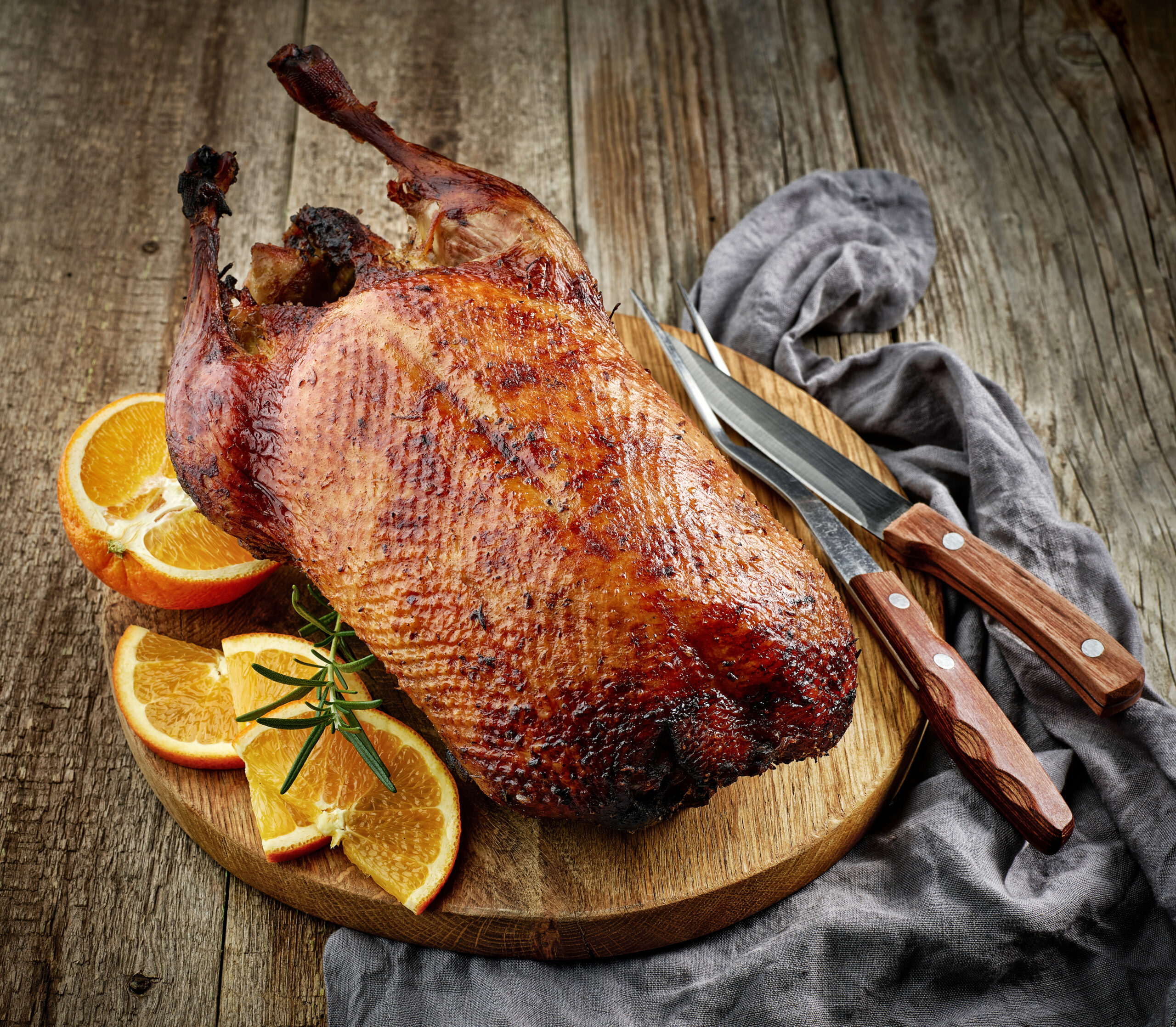 A grilled duck on a cutting board with orange slices on the side.