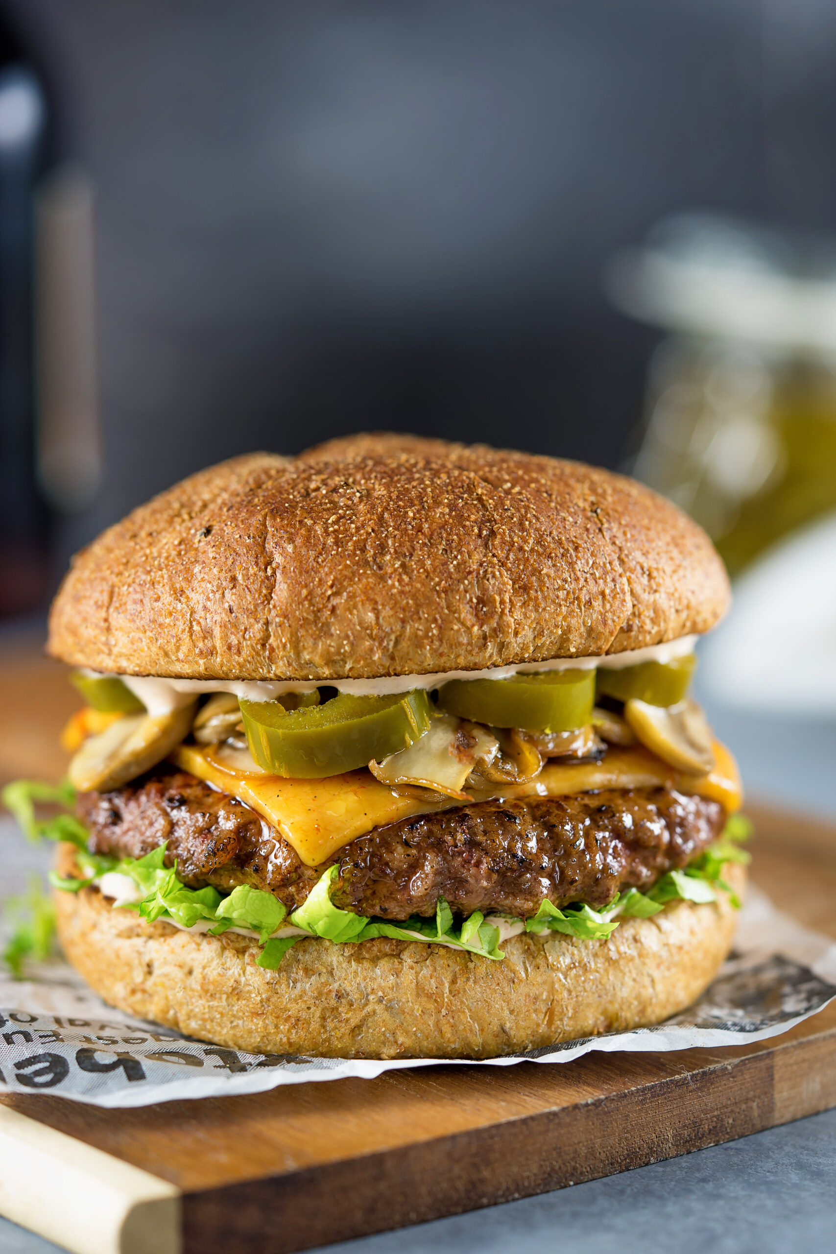 A beef burger topped with onions, jalapeno and cheese.