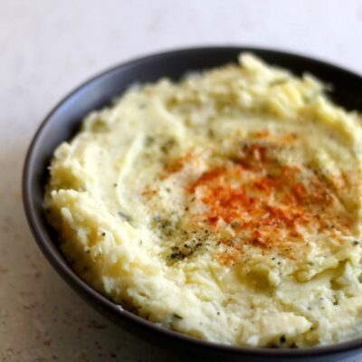 A bowl of mashed potatoes with paprika sprinkled on top