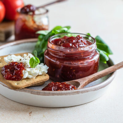 A jar of tomato jam with crackers on the side.
