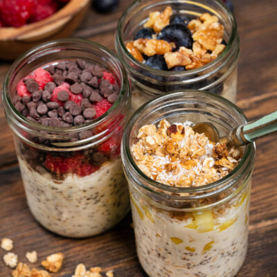 Overnight oats with toppings like raspberries, chocolate chips, granola, blueberries, and granola