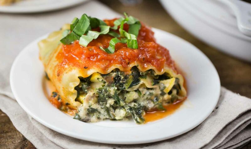 A lasagna roll filled with spinach on a white plate