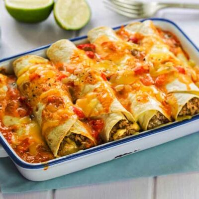 A casserole dish filled with sausage and egg enchiladas with cheese