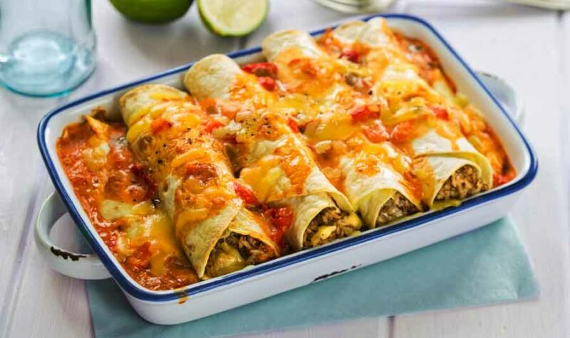 A casserole dish filled with sausage and egg enchiladas with cheese